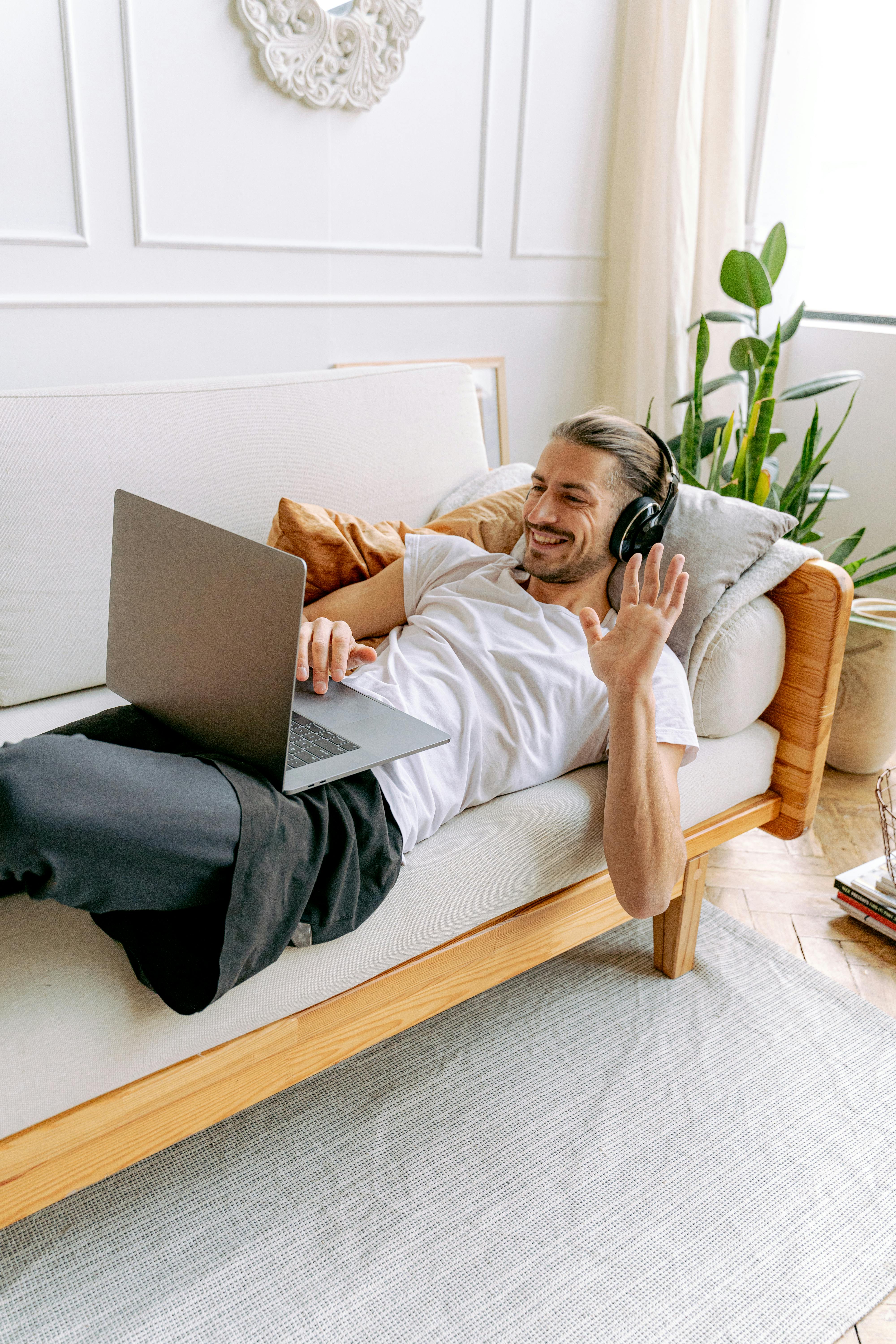 Man waving during a laptop video call at home