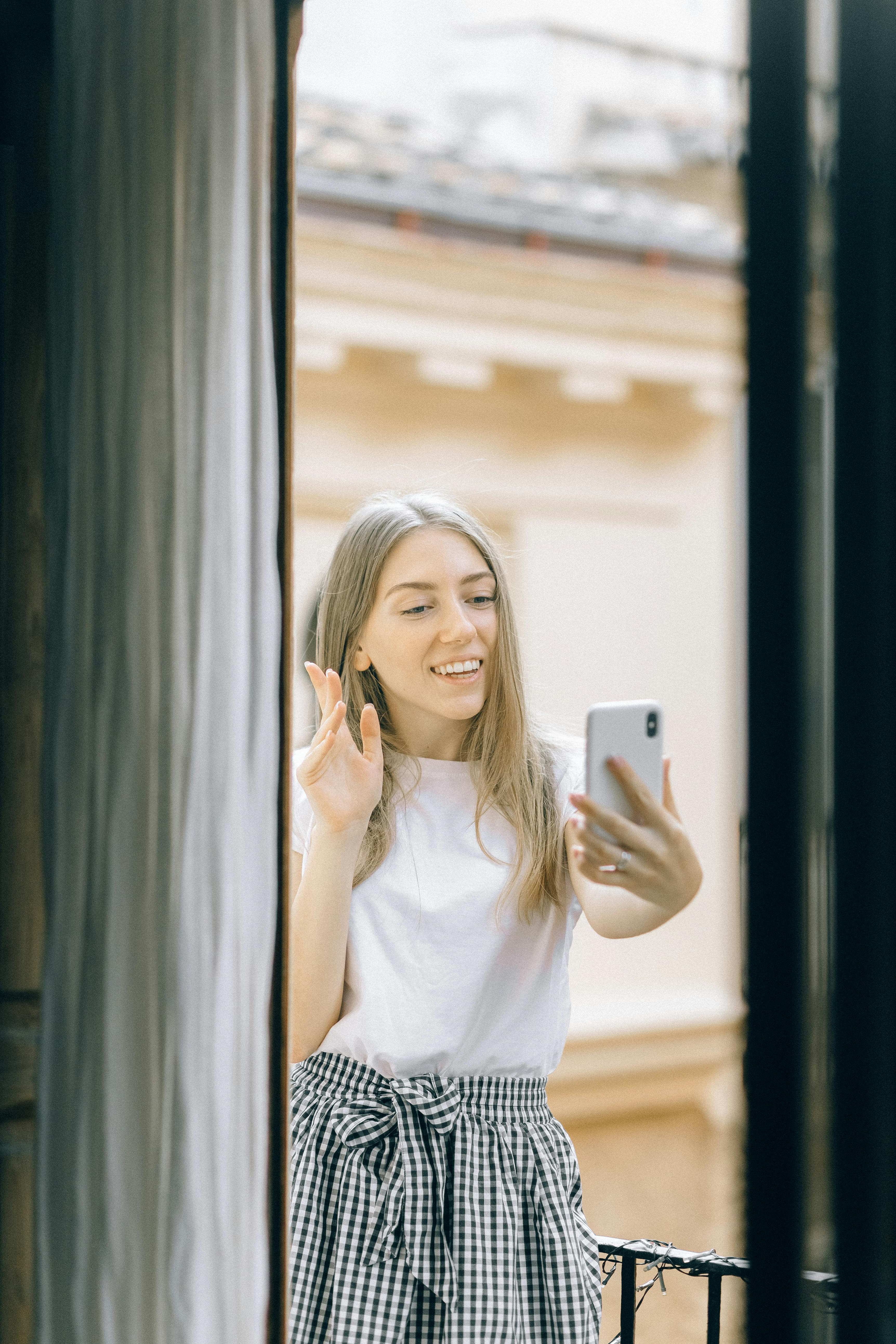 Woman smiling during a phone video call by a window